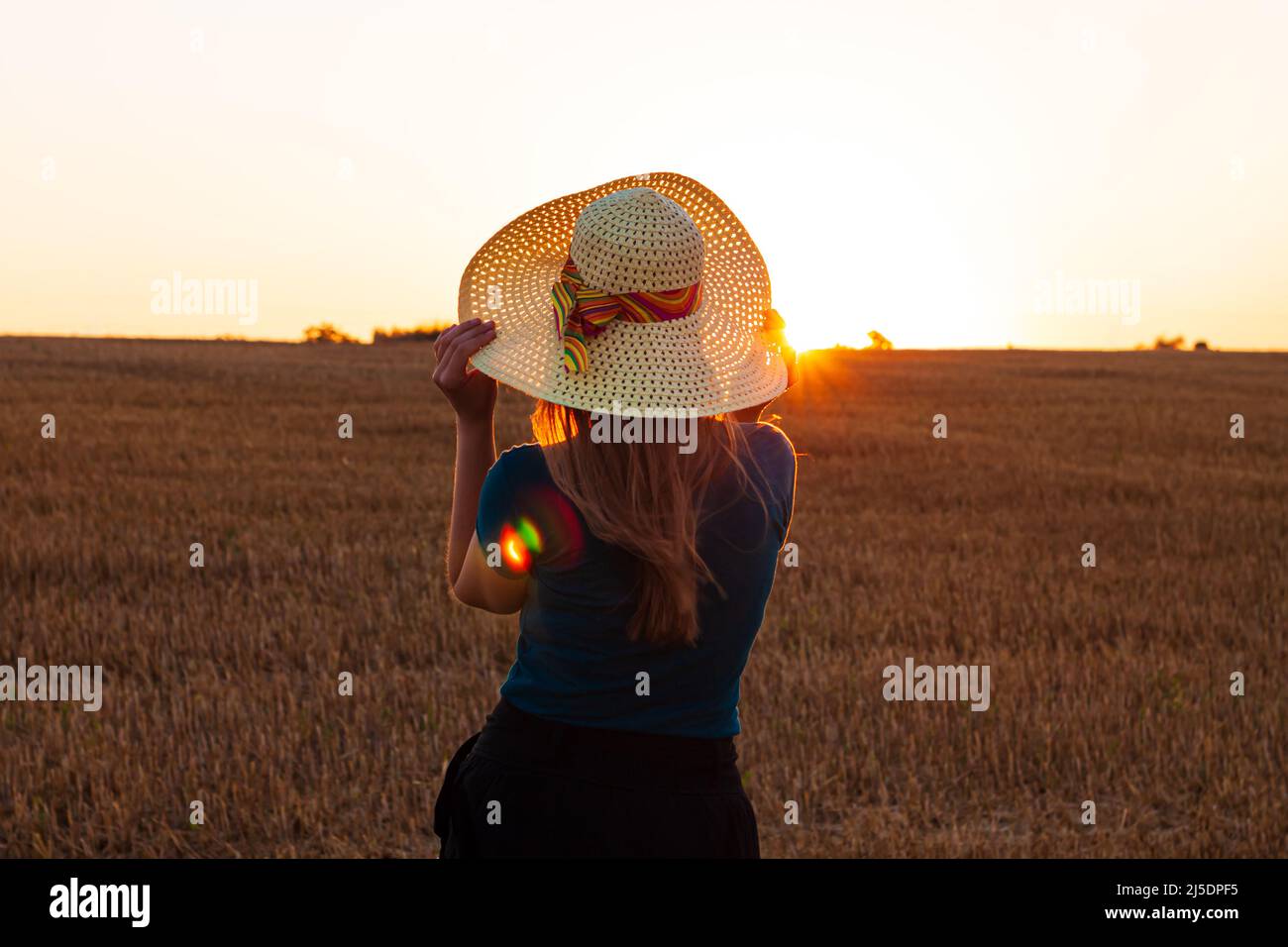 Adorable young girl in summer wheat field with straw hat in hands ...