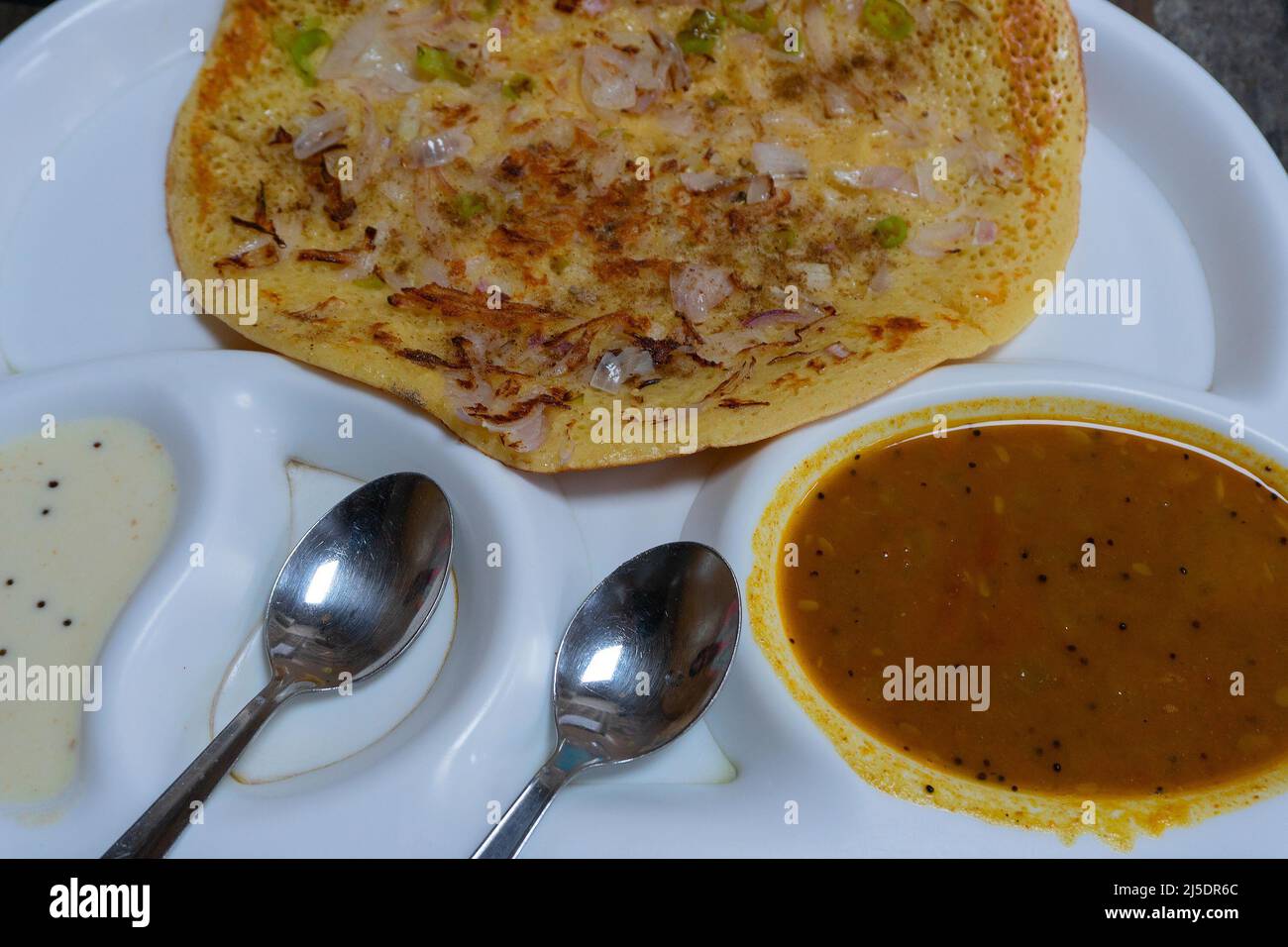 Uttapam is served with chutney on white plate, Indian vegetable dish. Stock Photo