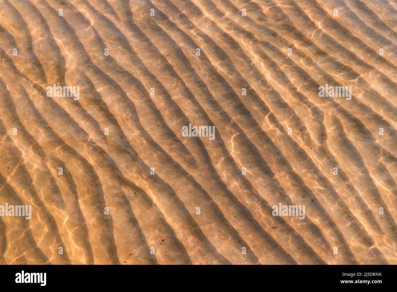 Sandy seabed with wavy relief pattern under shallow water, abstract natural background photo texture Stock Photo