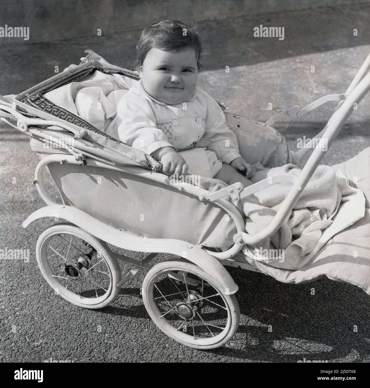 1960 historical an infant girl sitting in a pushchair of the era