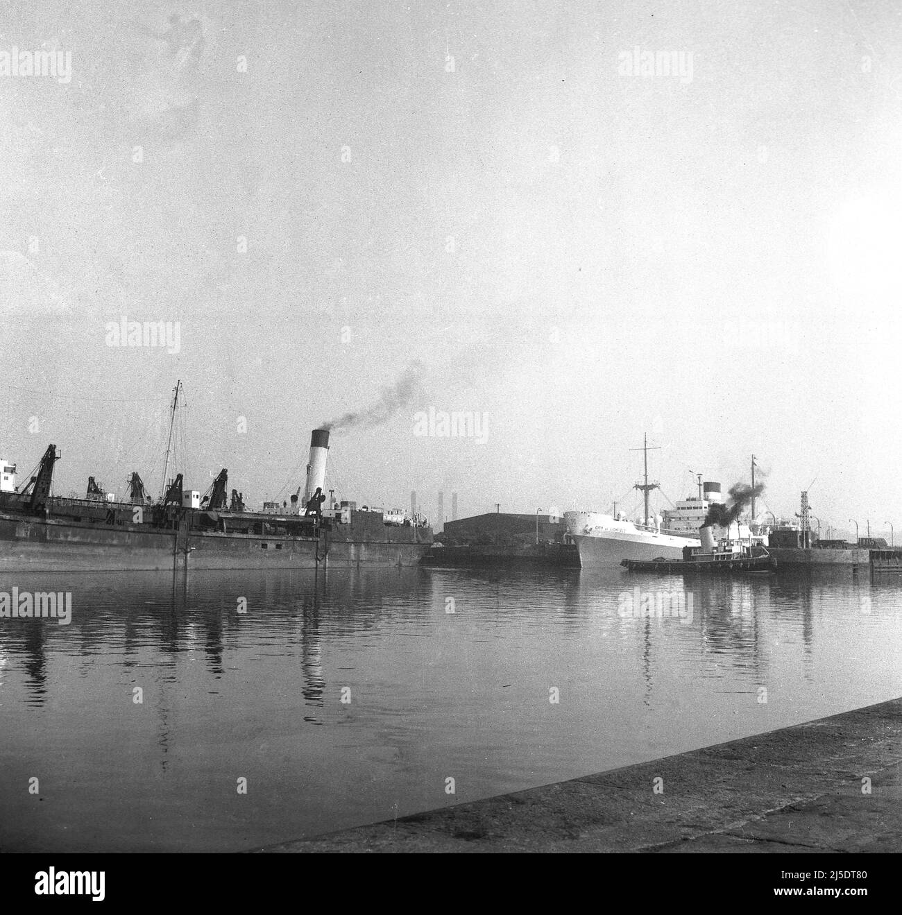 1961, historical, steam powered barges and cargo ships docked at Birkenhead, Liverpool, including the  Steel motor vessel, City of Lichfield, built by William Denny & Bros on the Clyde in Scotland. The Birkenhead docks were an inland waterway on the River Mersey, which closed in 1993. Stock Photo