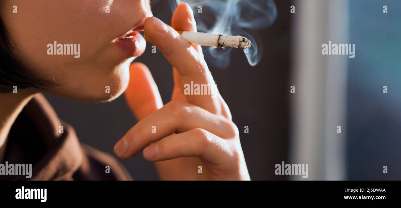 Girl is holding a cigarette in her hand, smoking closeup Stock Photo