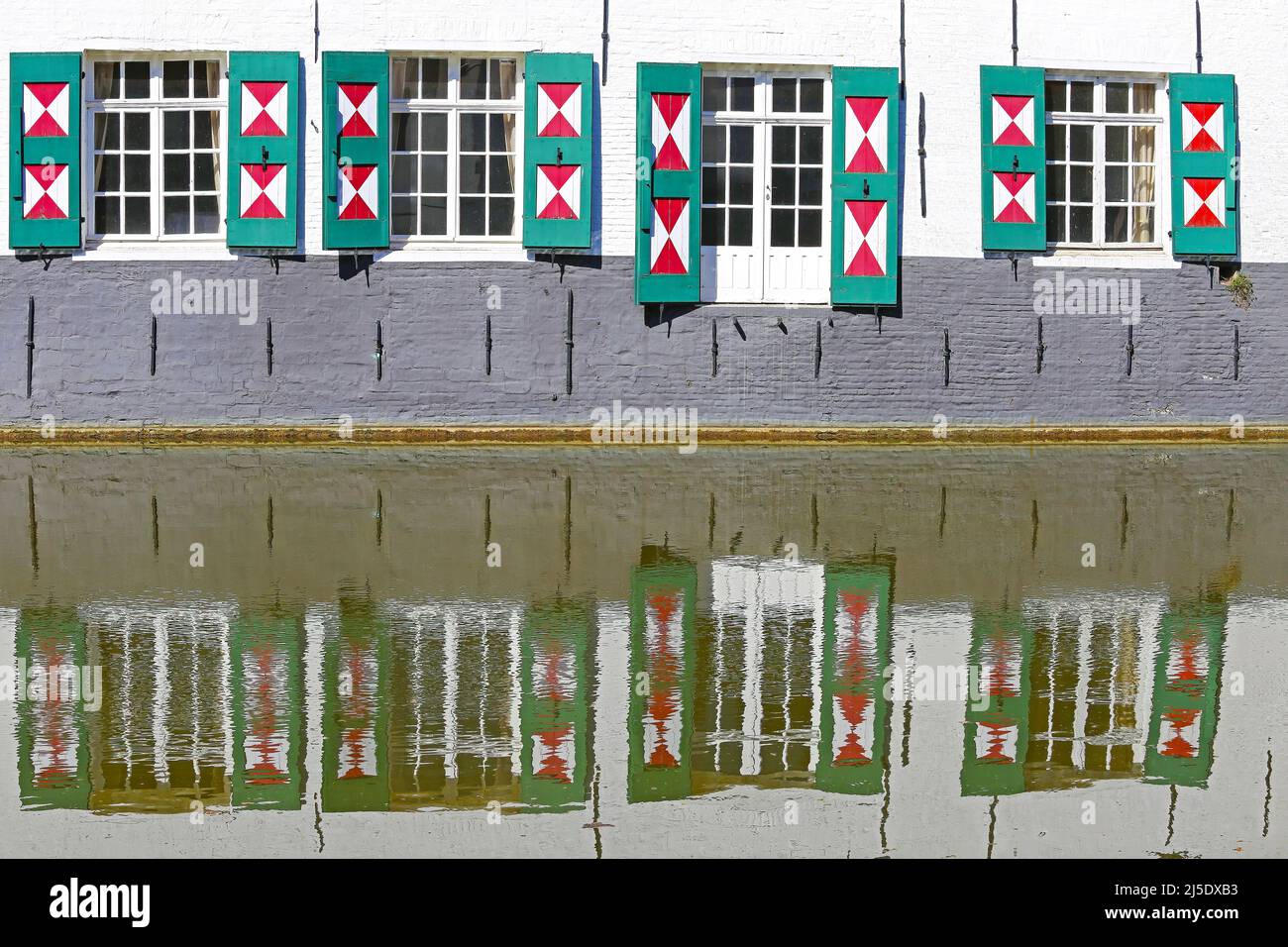 Closeup of ancient waterfront house facade, many glass windows, open exterior board batten shutters painted in triangle red white design - Lier, Belgi Stock Photo