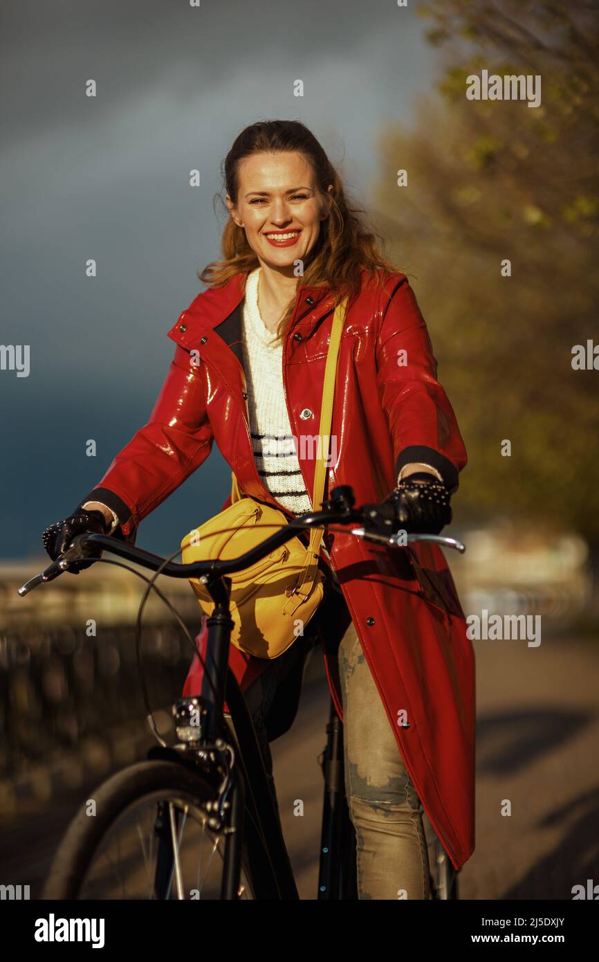 happy elegant middle aged woman in red rain coat outside on the city ...