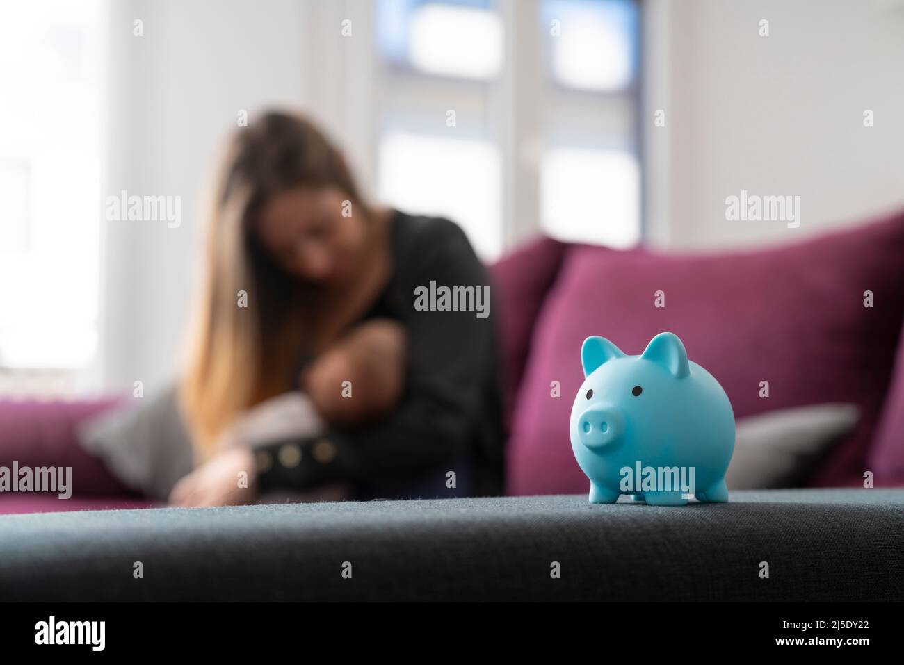 Piggy bank on a sofa with a mother with her baby Stock Photo