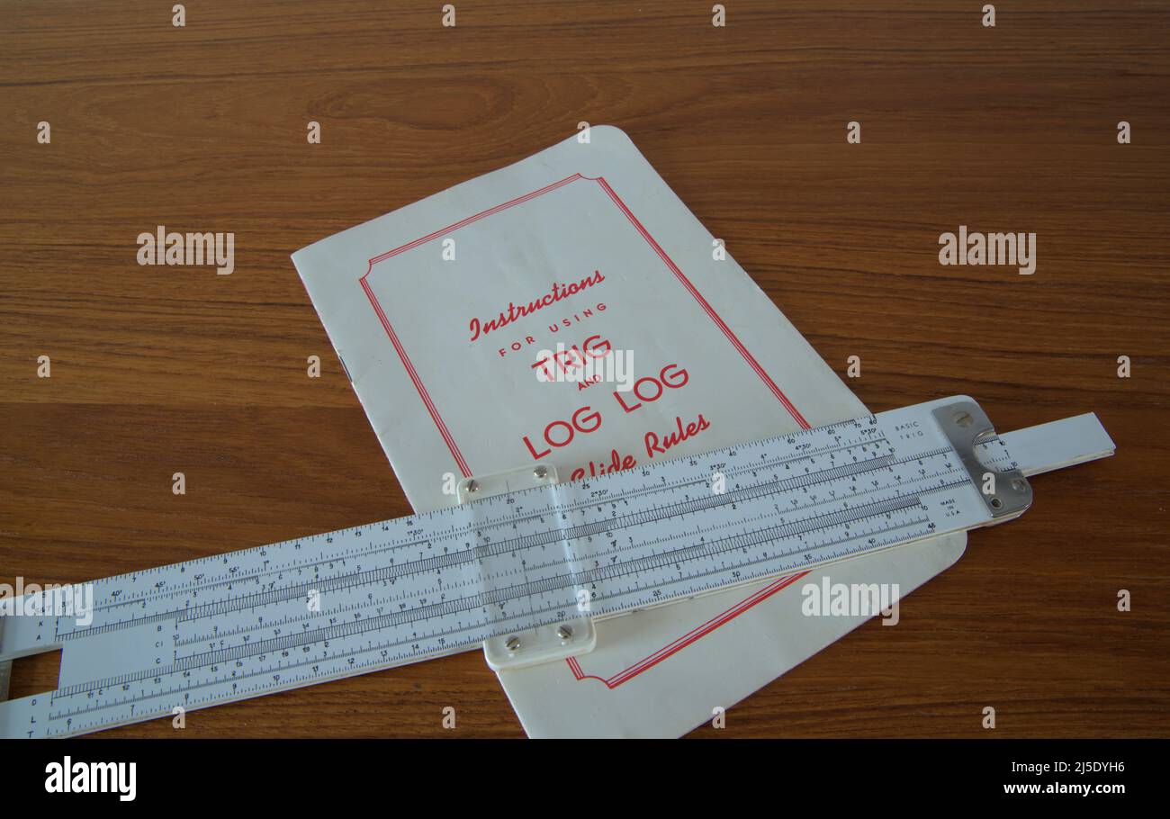 Slide rule is a no power computer and was a popular tool for people in the scientific world . An instruction book is shown with this retro item. Stock Photo