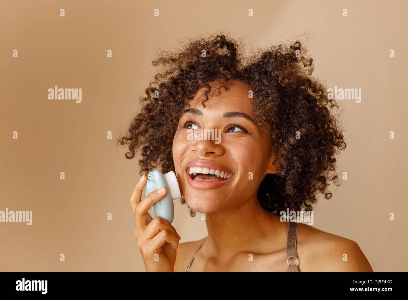 Multiethnic woman toothy smiling on beige background of studio Stock Photo