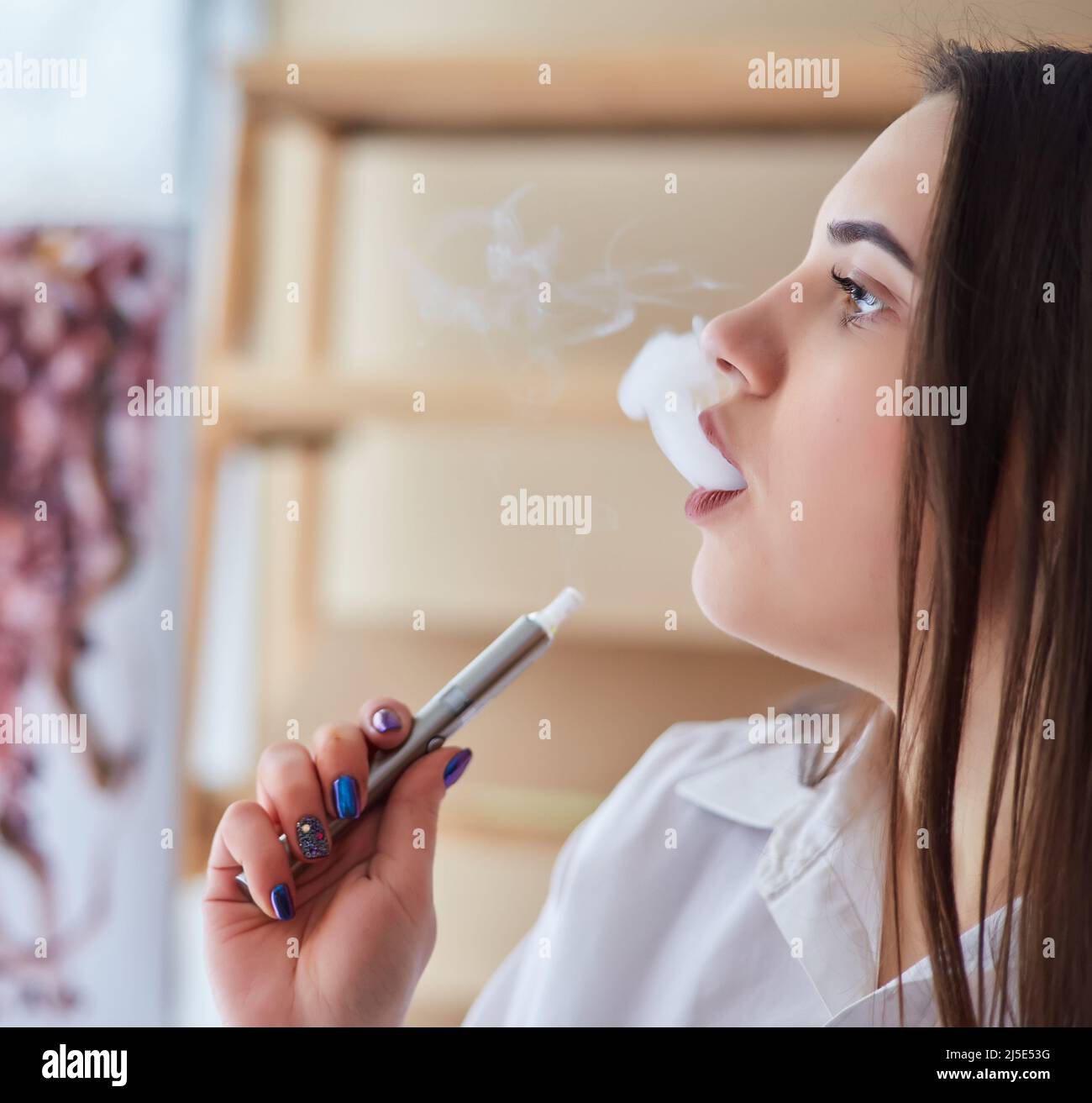 Happy vaper girl with vaping device in hand.Quit smoking nicotine  cigarettes, start vaporizing. Attractive young woman Stock Photo