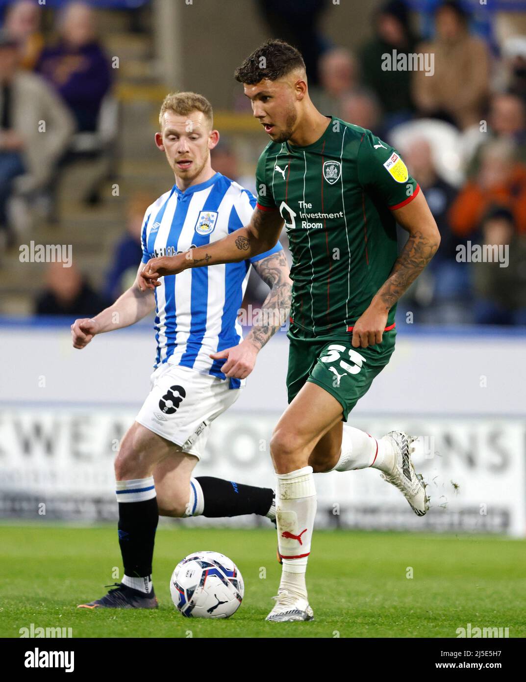 Huddersfield Town's Lewis O'Brien (left) and Barnsley's Matthew Wolfe battle for the ball uring the Sky Bet Championship match at John Smith's Stadium, Huddersfield. Picture date: Friday April 22, 2022. Stock Photo
