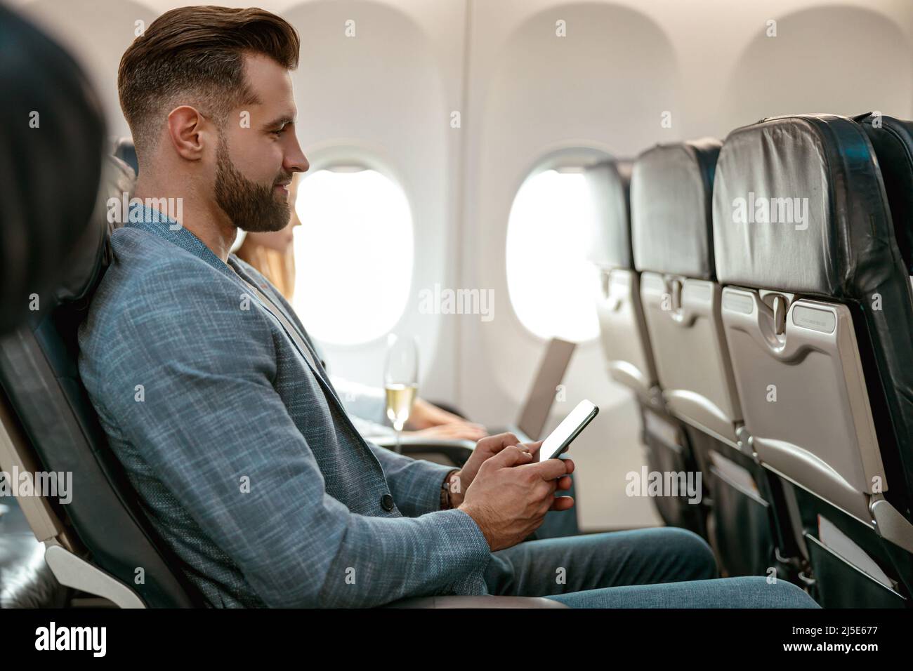 Bearded man using mobile phone in airplane Stock Photo