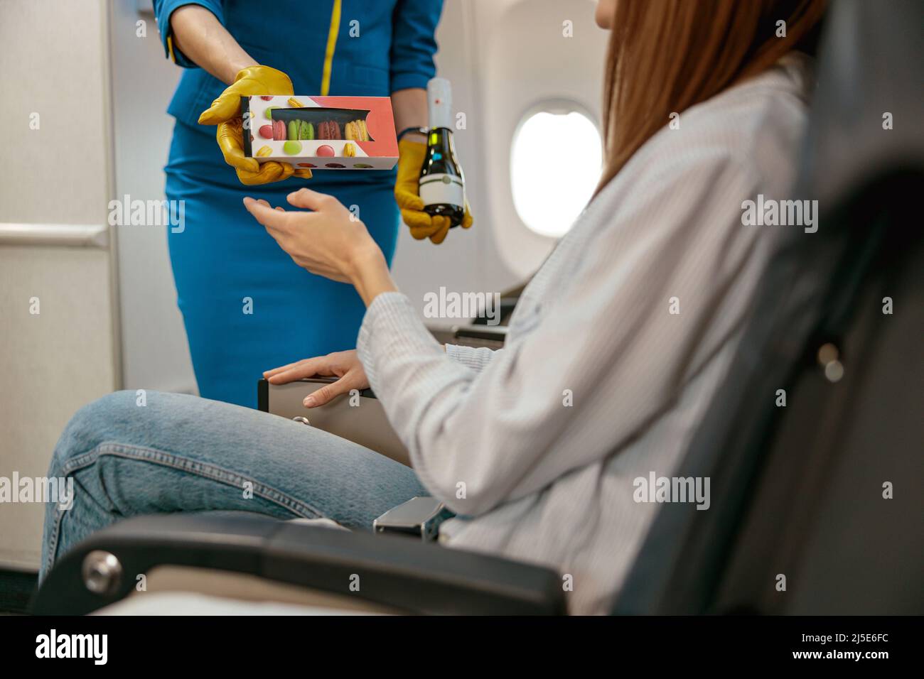 Stewardess offering food and drink to woman in airplane Stock Photo