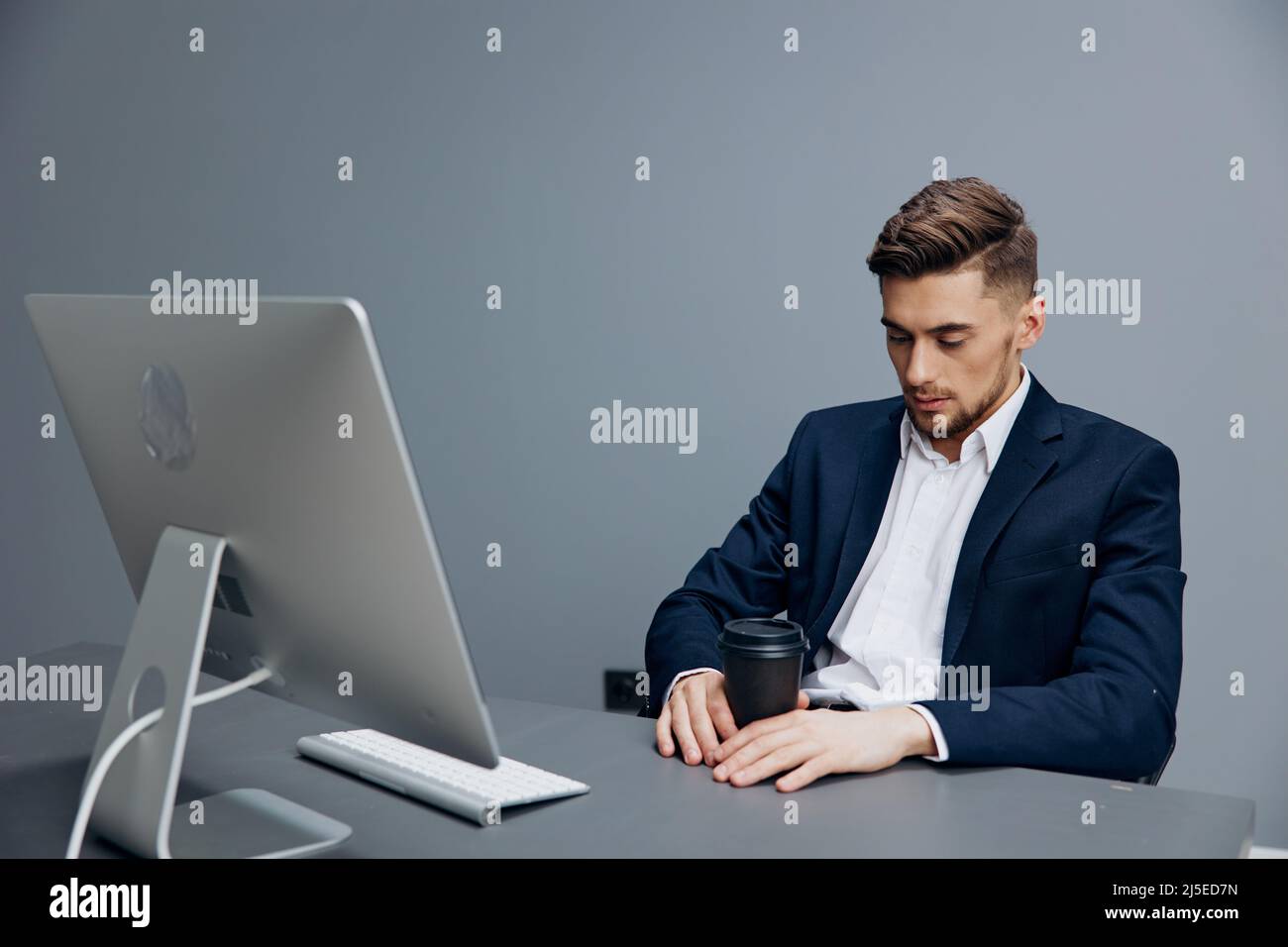 handsome businessman tired glass of coffee works in front of a computer ...