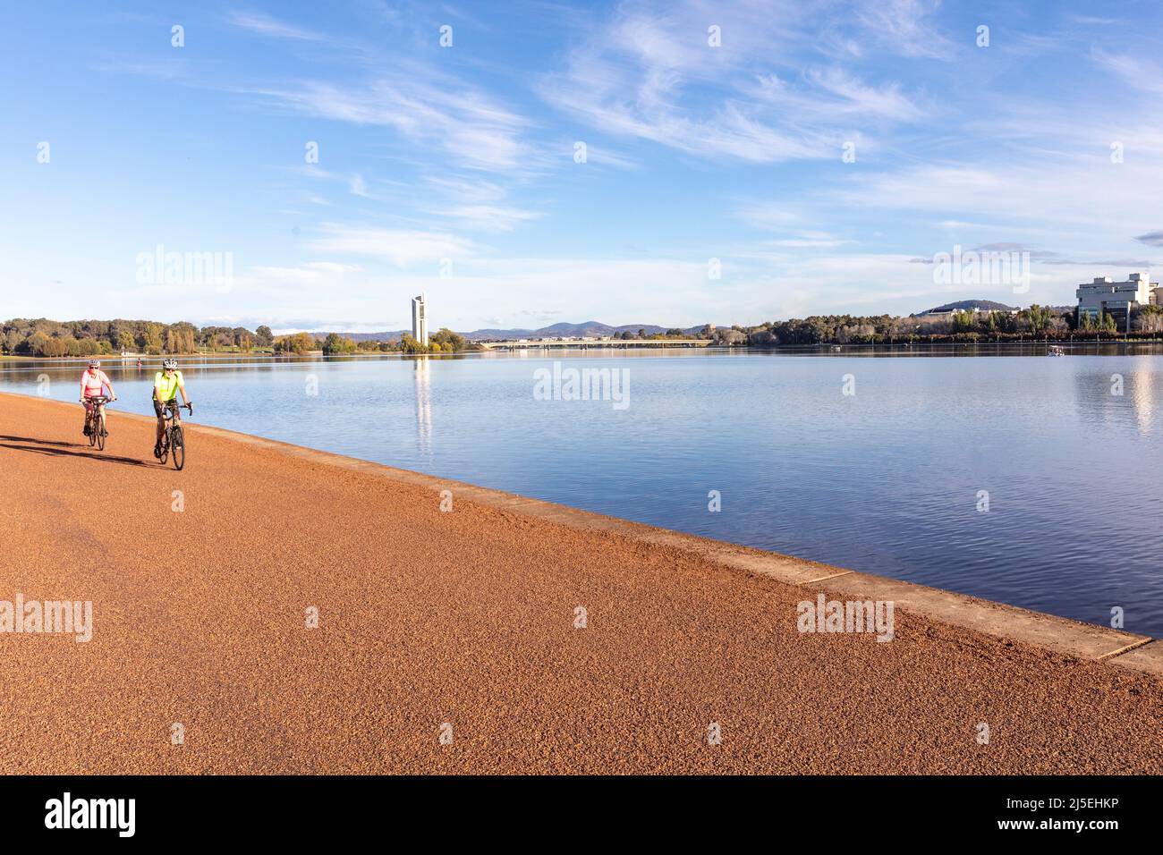 Cyclists at Lake Burley Griffin with national carillon and high court