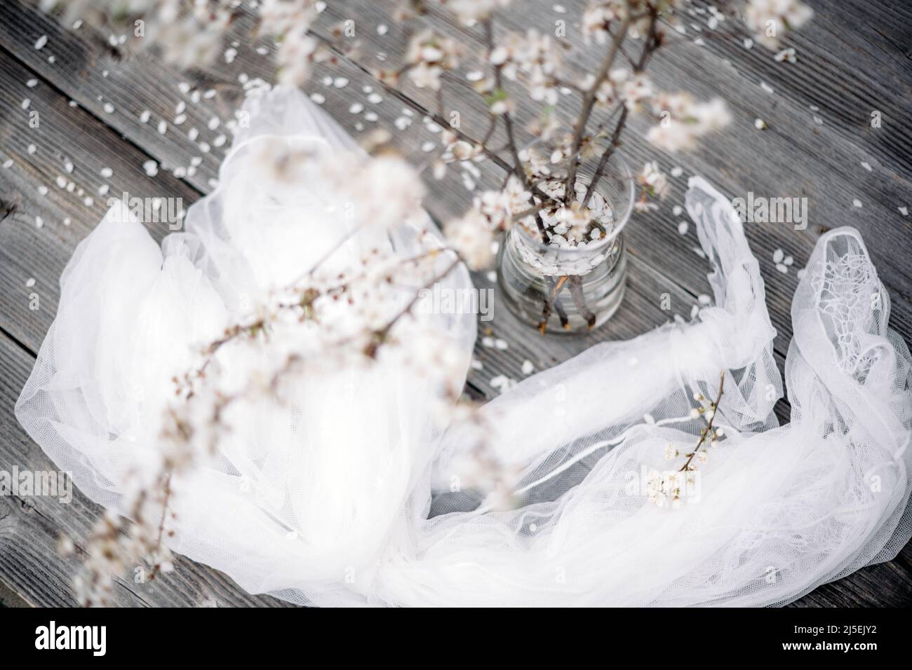 White cherry flowers twigs on glass vase on wooden table on spring time Stock Photo