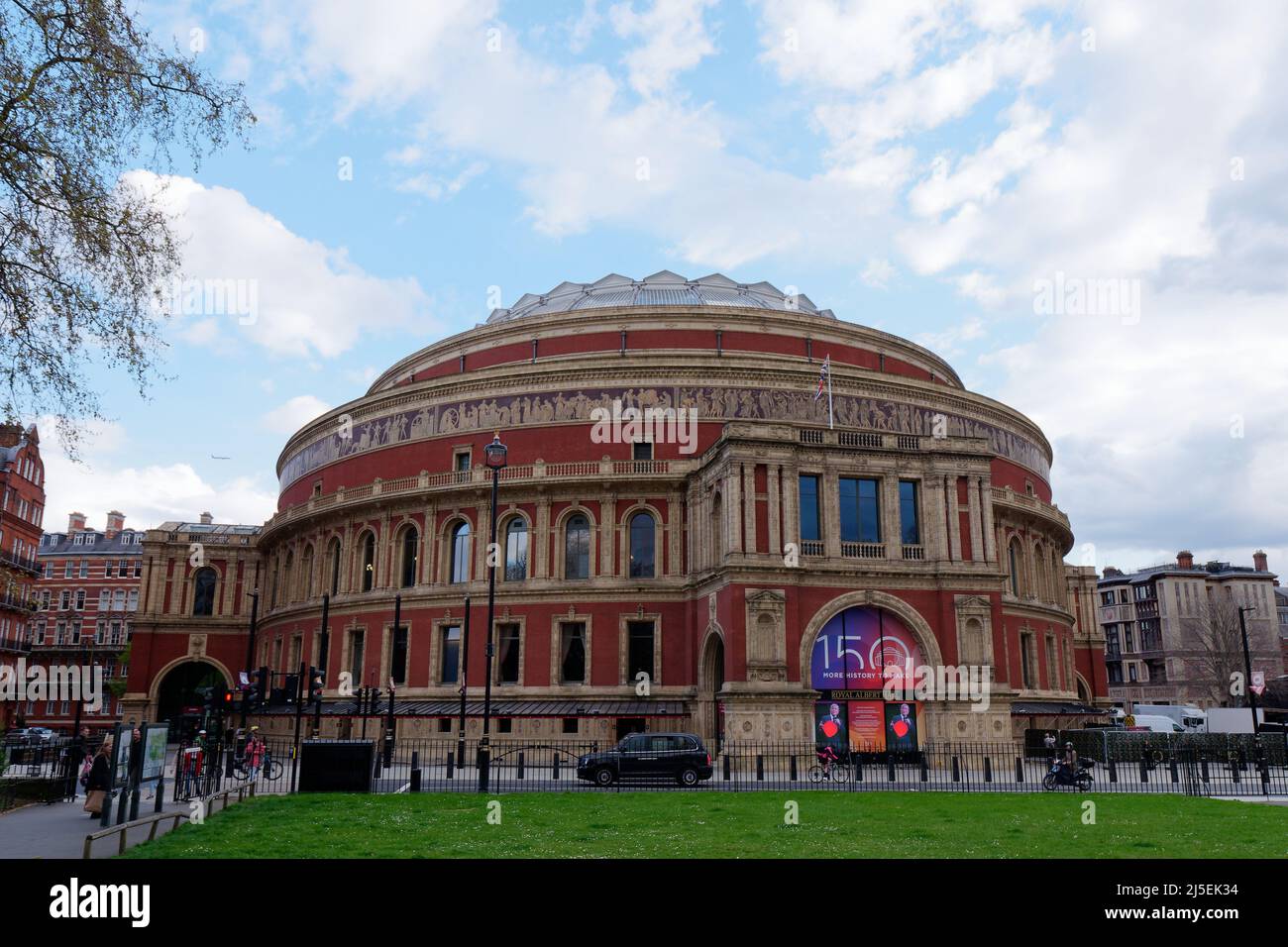 London, Greater London, England, April 13 2022: Taxi and Motorbike pass the Royal Albert Hall, a famous concert hall in South Kensington. Stock Photo
