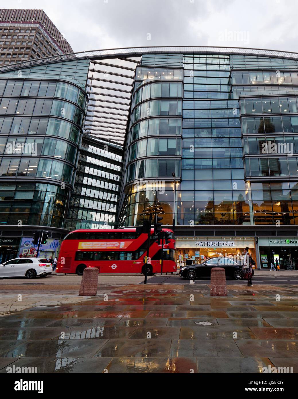 London, Greater London, England, April 13 2022: Victoria Street in Westminster as a bus passes by and wet pavement in the foreground. Stock Photo