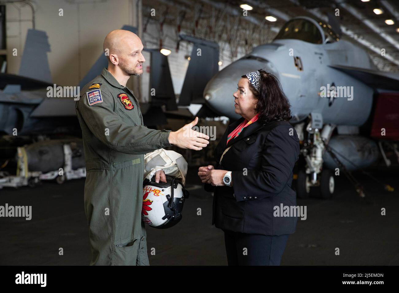 Dame Karen Pierce, Her Majesty's Ambassador to the United States of America, speaks with Lt. Thomas Sharp, a Royal Navy exchange pilot, attached to the 'Golden Warriors' of Strike Fighter Squadron (VFA) 87, serving on USS Gerald R. Ford (CVN 78), April 21, 2022. Her Majesty's Ambassador and staff visited Ford to observe flight operations and discuss Ford-class unique systems and equipment. Ford is underway in the Atlantic Ocean conducting carrier qualifications and strike group integration as part of the ship’s basic training phase. (U.S. Navy photo by Mass Communication Specialist 2nd Class A Stock Photo