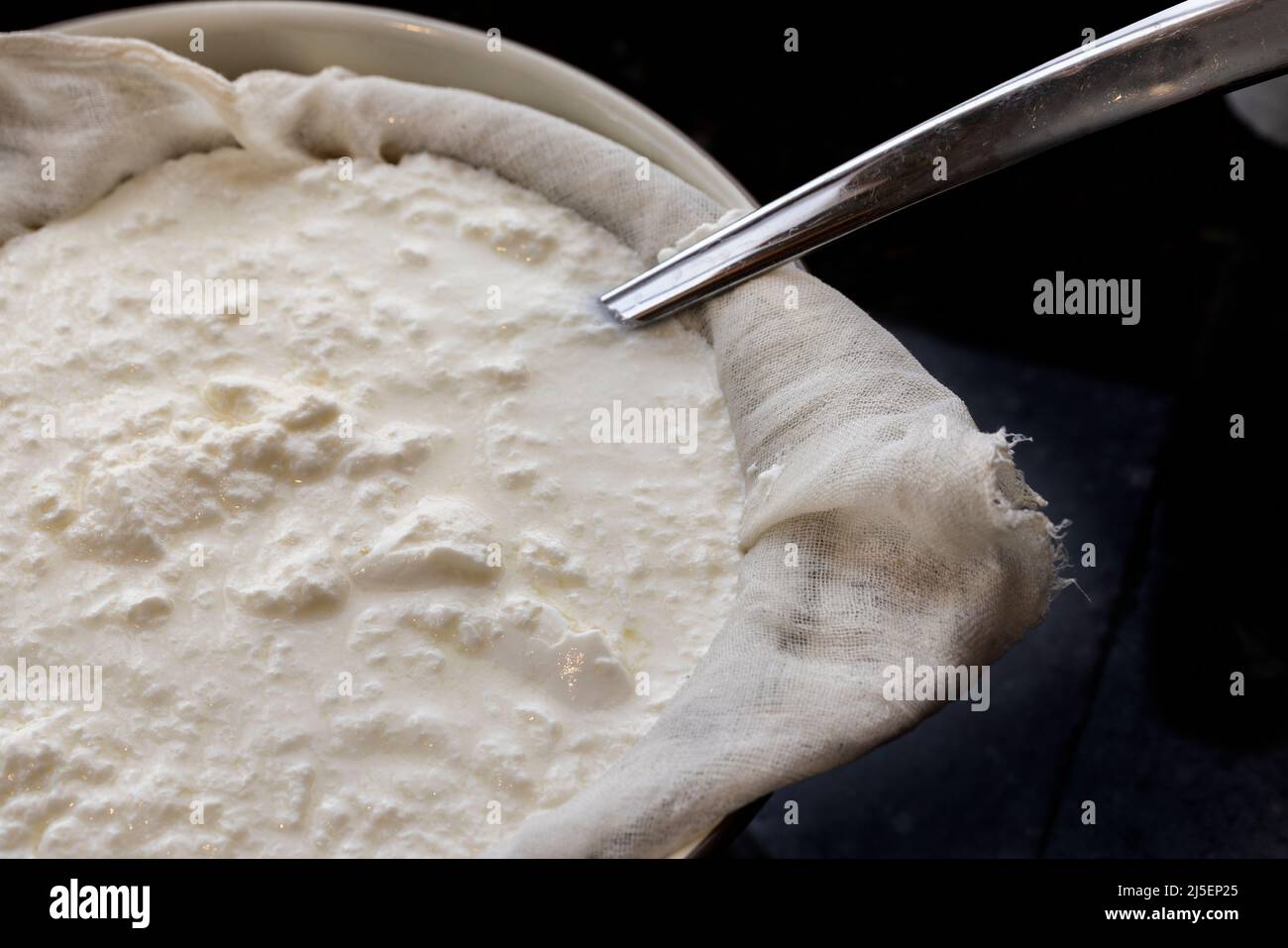 Seperating the whey from the homemade yogurt with a cheesecloth and strainer in a bowl Stock Photo