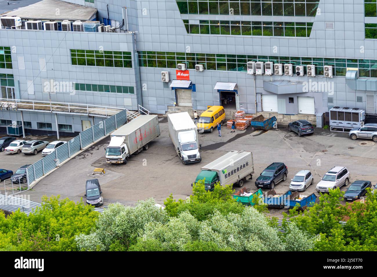 Kemerovo, Russia - June 24, 2021. A large building with cars and unloading trucks, the backyard of a multi-level shopping center or a product warehous Stock Photo