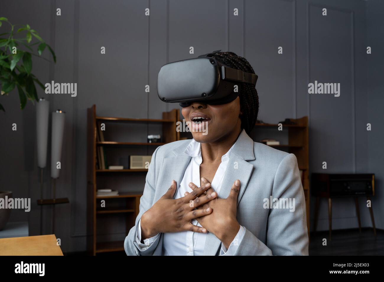 Emotional shocked african businesswoman in VR headset immersed in 3D