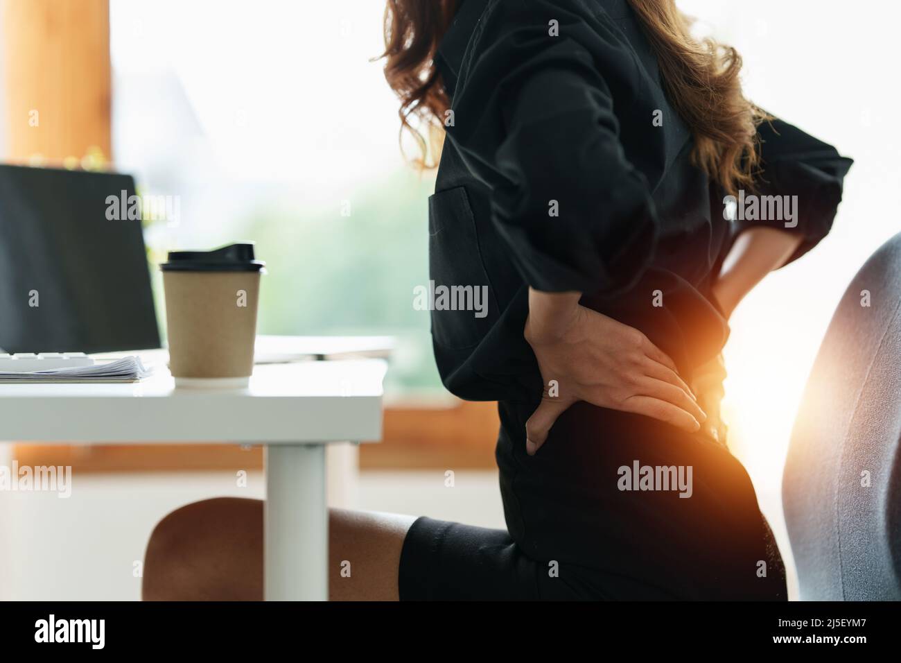 Asian Business woman holding her back pain from overworking. Office syndrome. Stock Photo