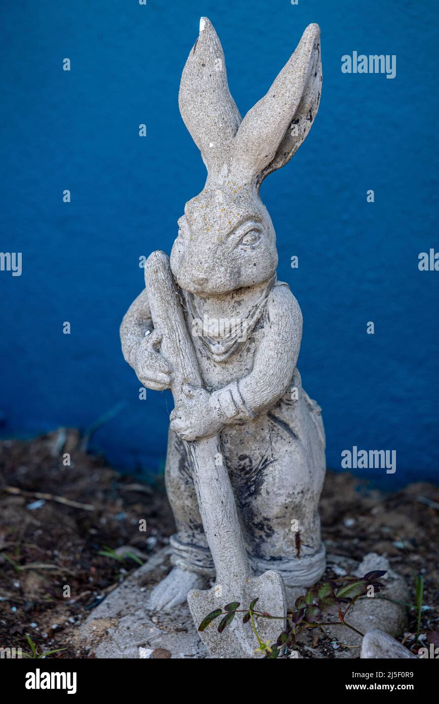 A concrete statue of a rabbit holding a shovel. Stock Photo
