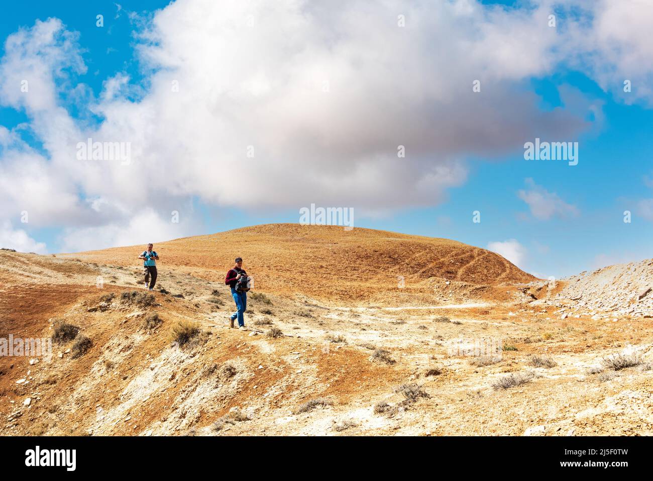 Hikers climb a high hill in a desert area Stock Photo - Alamy