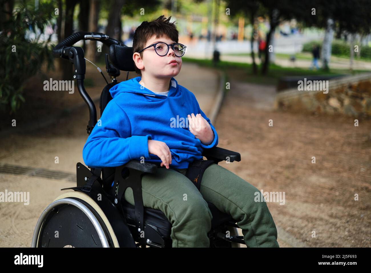 Disabled boy in wheelchair enjoying the day outdoors in the park. Stock Photo