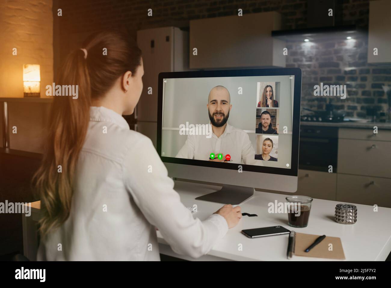 Back view of woman talking to her colleagues in a video conference on computer. Stock Photo