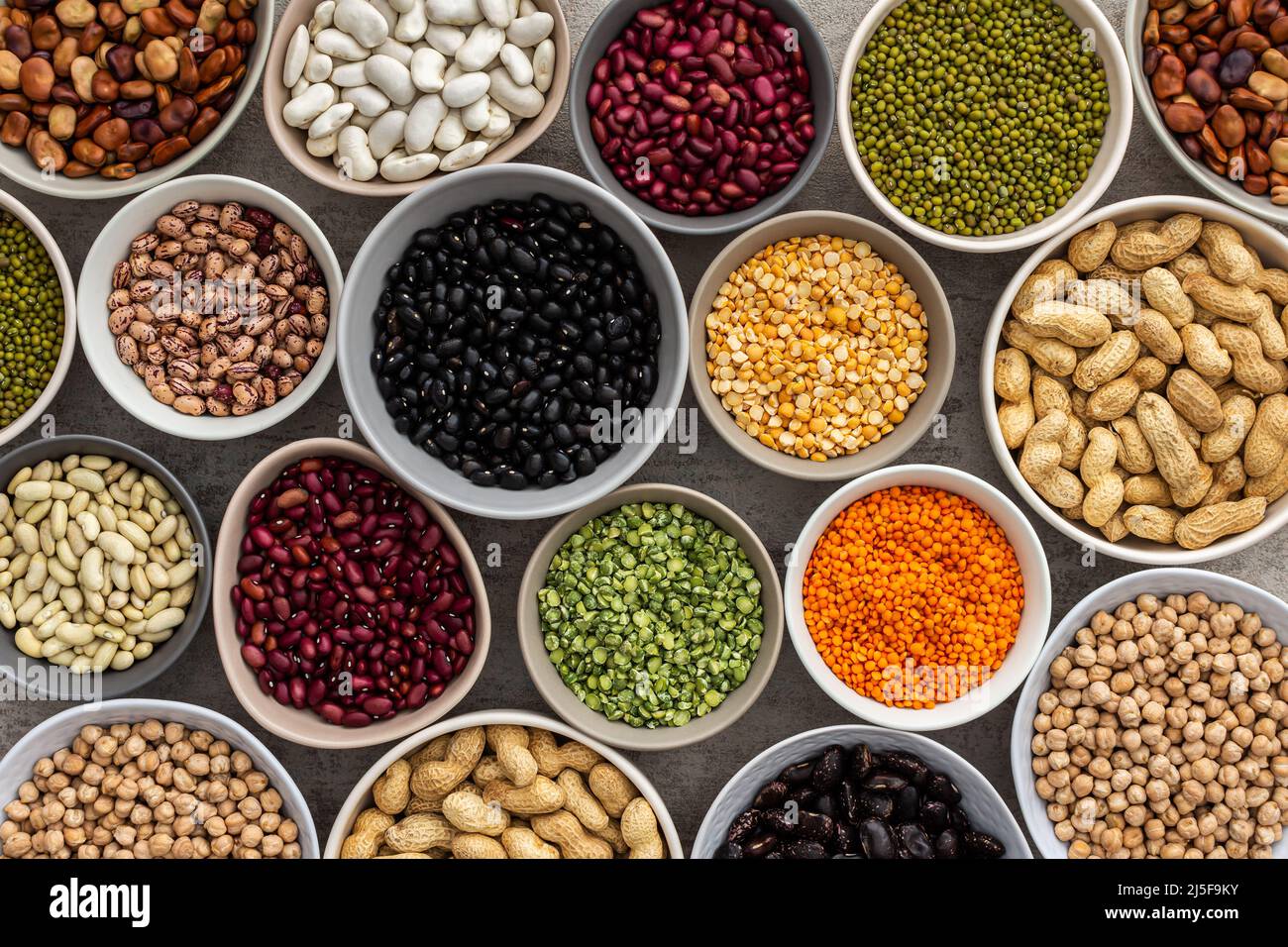 Different types of legumes in bowls, green with yellow peas and mung