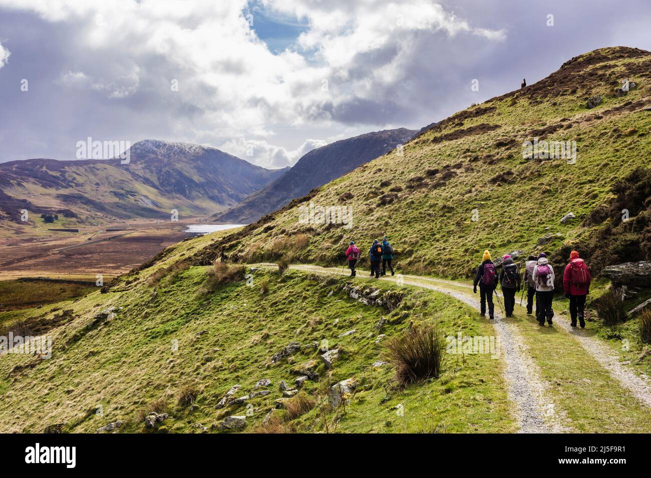 A group of hikers walking down a track into Cwm Eigiau valley in mountains of Snowdonia National Park. Conwy, north Wales, UK, Britain Stock Photo