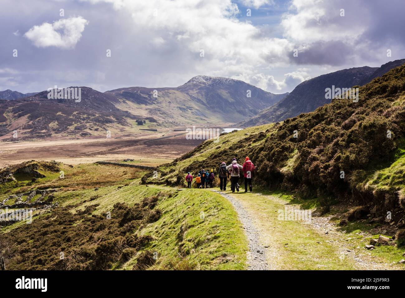 A group of hikers walking down a track into Cwm Eigiau valley in mountains of Snowdonia National Park. Conwy, north Wales, UK, Britain Stock Photo