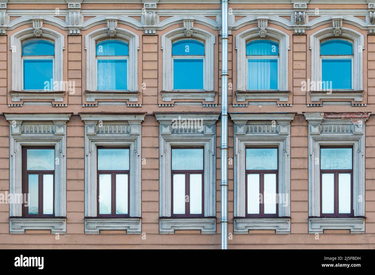 Many windows in a row on the facade of the urban historic apartment ...
