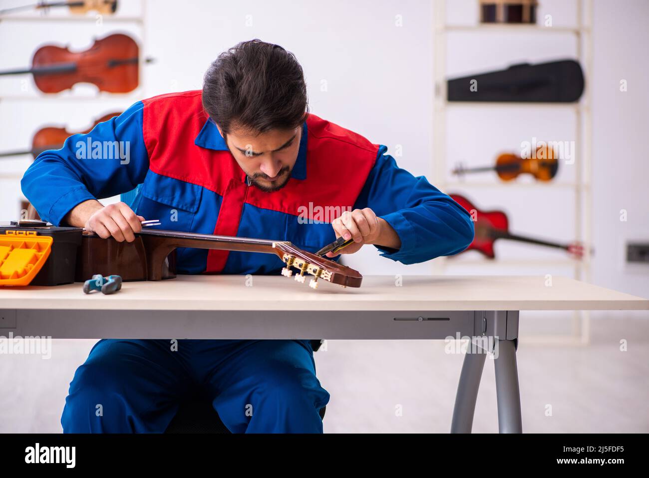 Young repairman repairing musical instruments at workplace Stock Photo