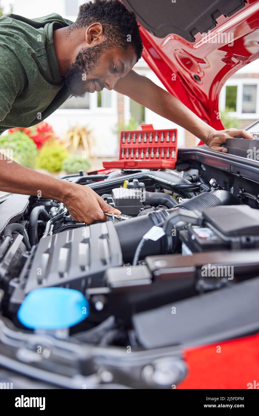 Man Working Under Hood Of Car Fixing Engine With Wrench Stock Photo