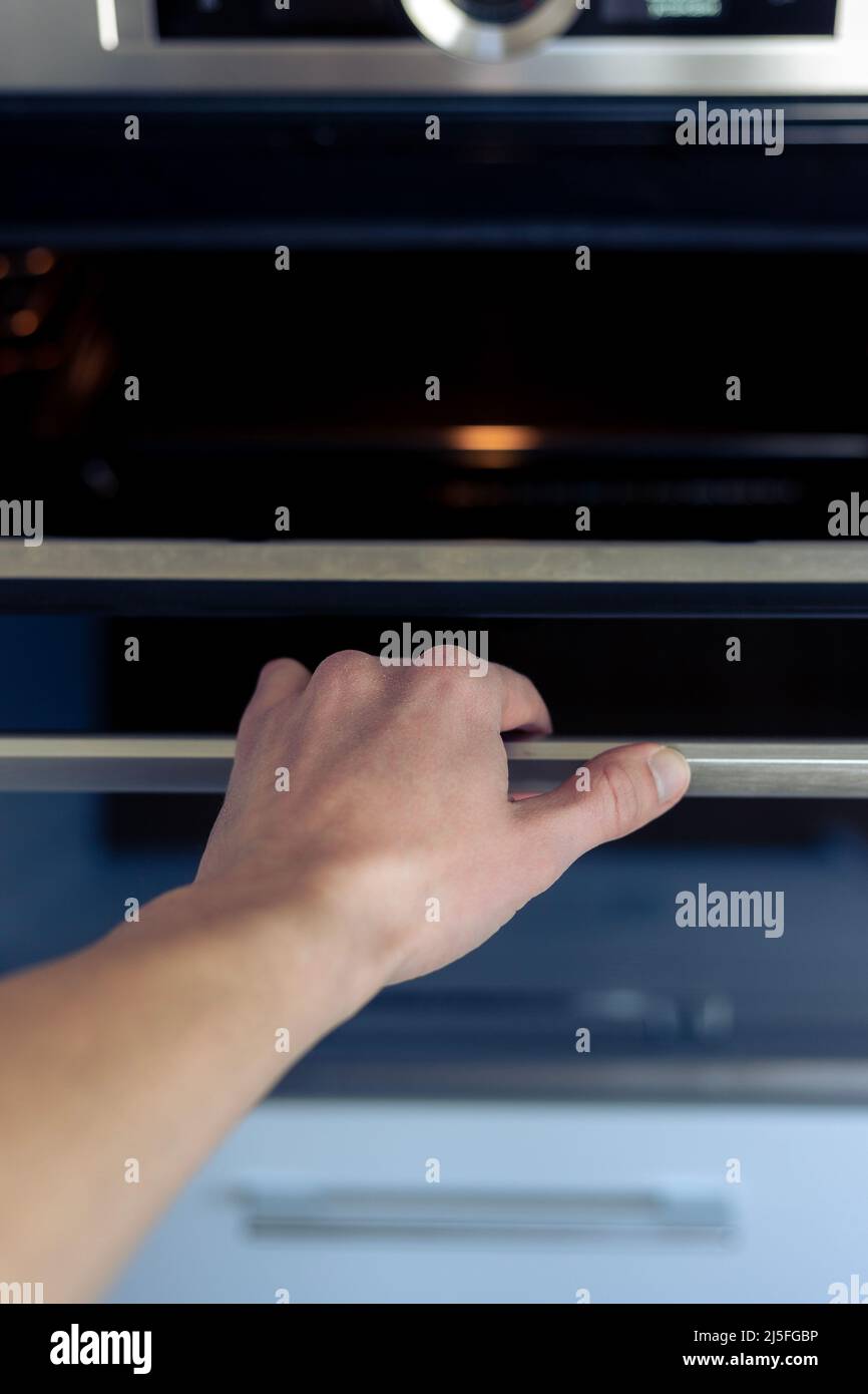 The hand opens the oven door. Kitchen equipment Stock Photo Alamy