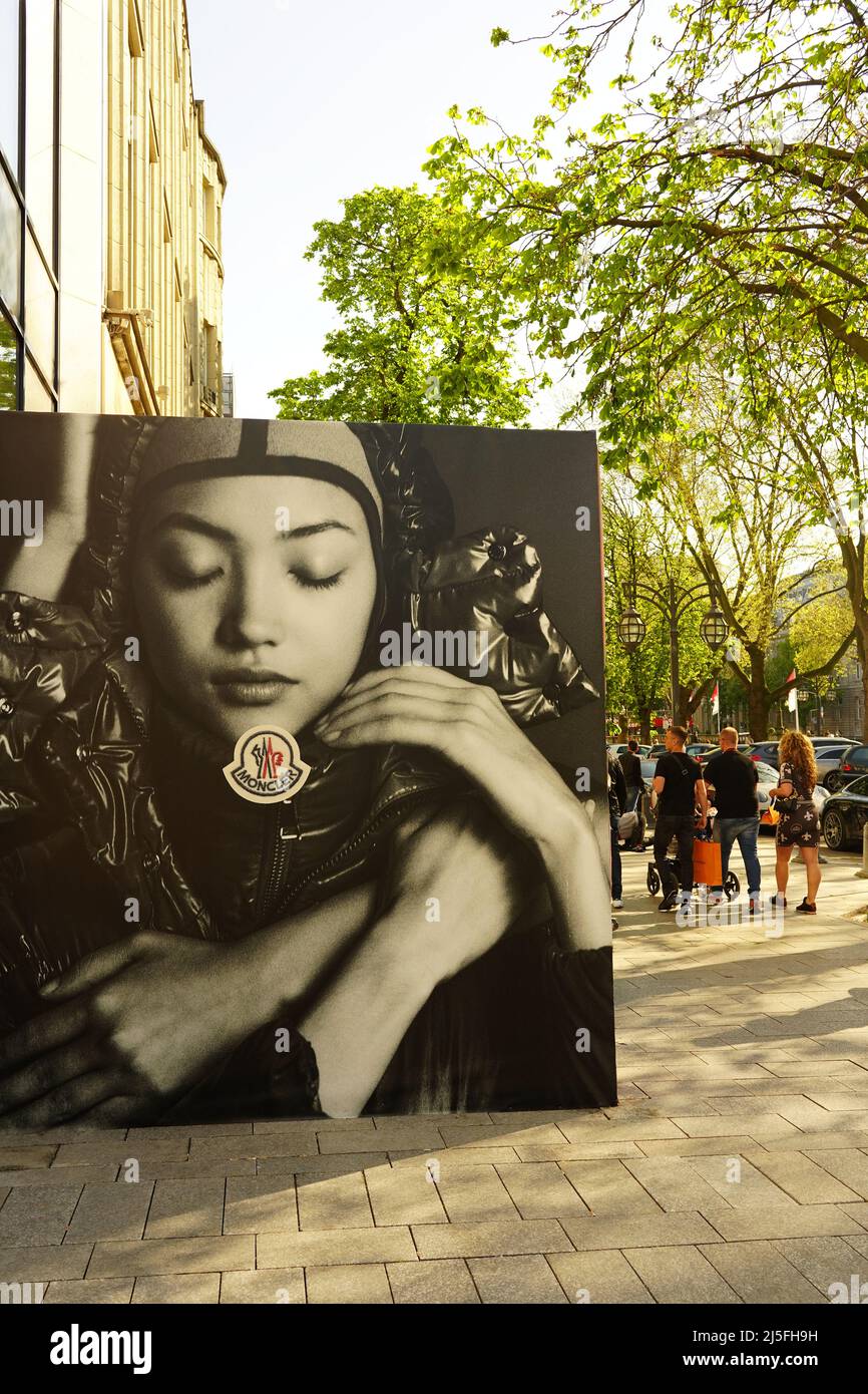 The shopping boulevard Königsallee in Düsseldorf/Germany with Moncler advertising poster. Stock Photo