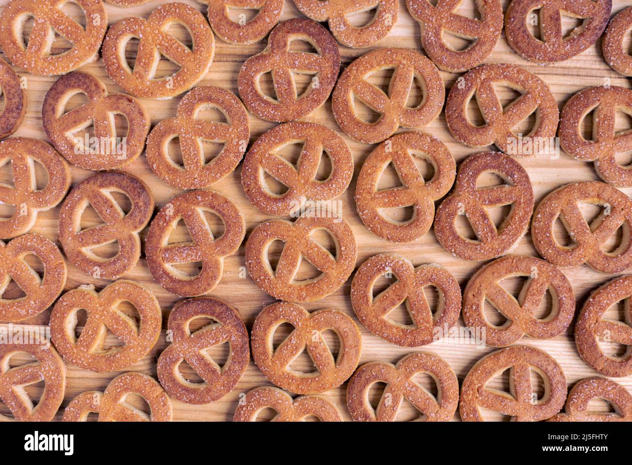 Pretzels sprinkled with sugar lie on a wooden surface Stock Photo
