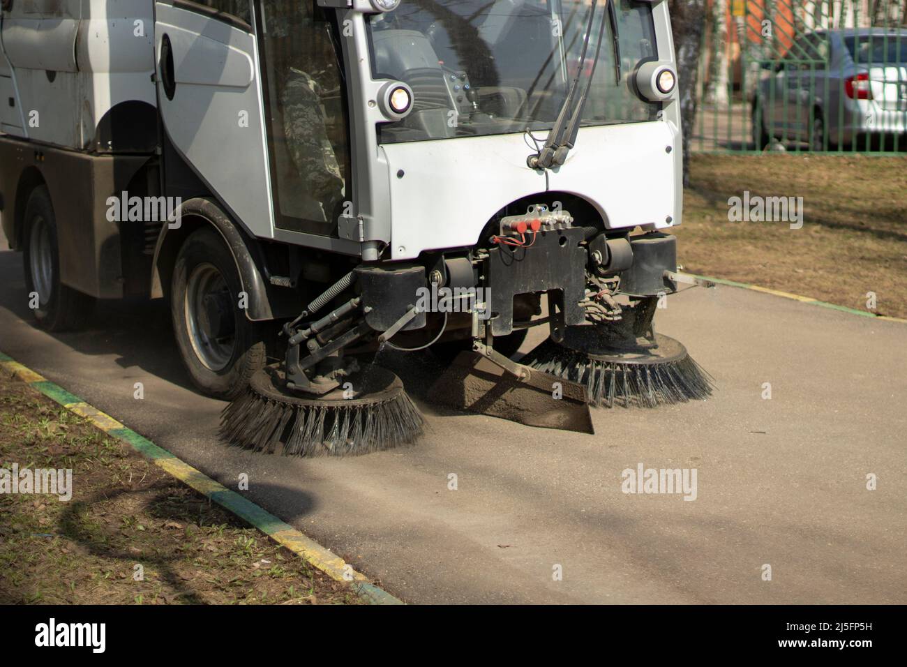 The sweeper is sweeping the asphalt. Cleaning the path with a cleaning vehicle. Cleaning the