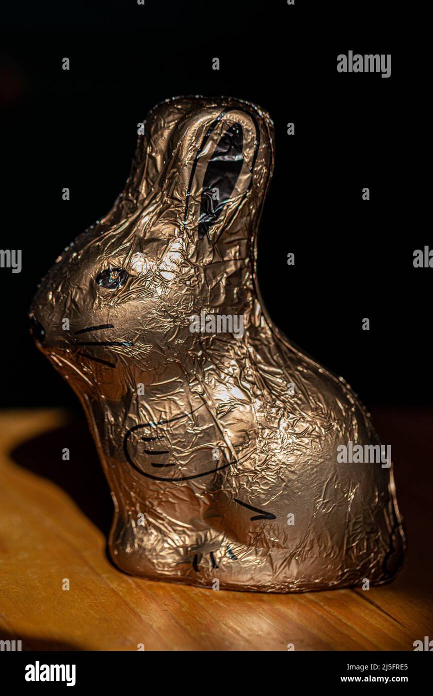 Easter bunny, in golden wrapping, standing sideways. Stock Photo