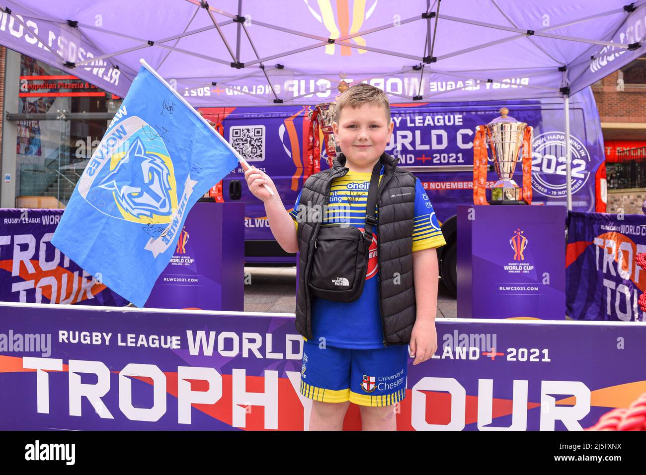 A young Warrington Wolves fan poses for photos next to the Rugby League World Cup Trophies in the fan zone before the game Stock Photo
