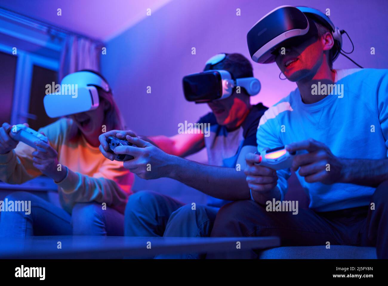 Friends playing virtual reality games using joysticks while sitting on