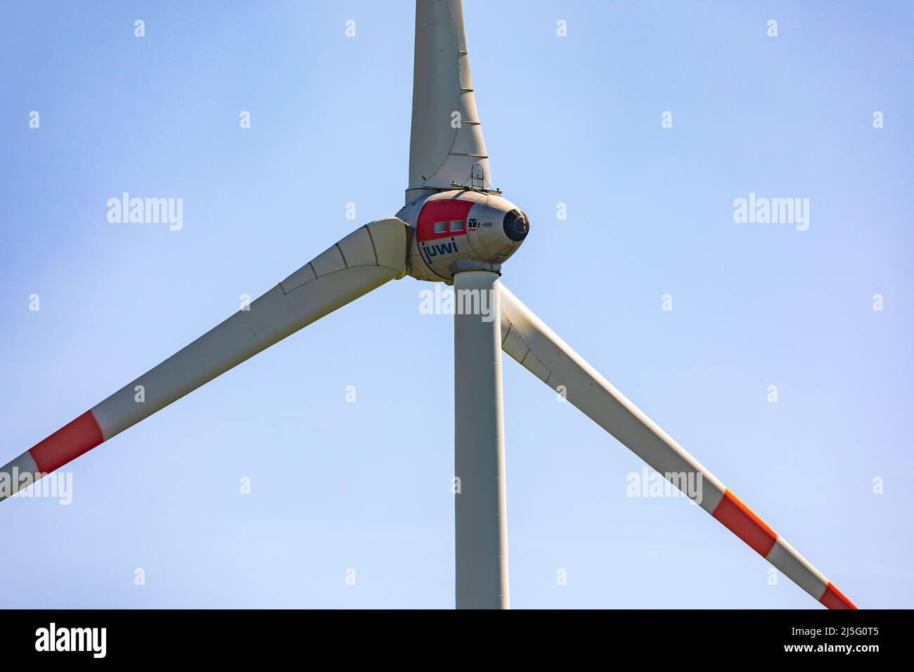 A close-up of a wind turbine with three huge rotor blades isolated against a blue sky Stock Photo