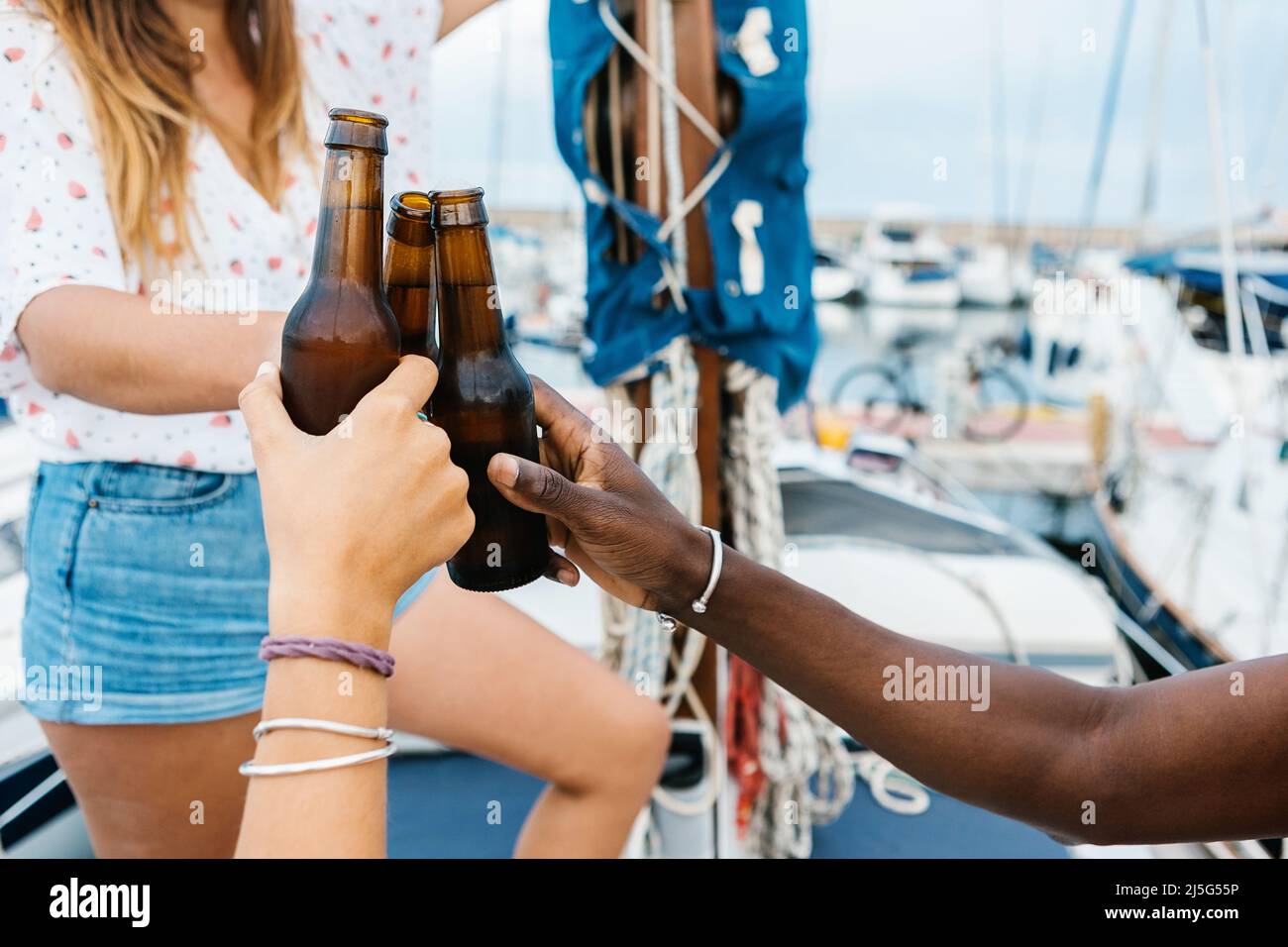 Multiracial friends cheering with beer on boat in summer Stock Photo