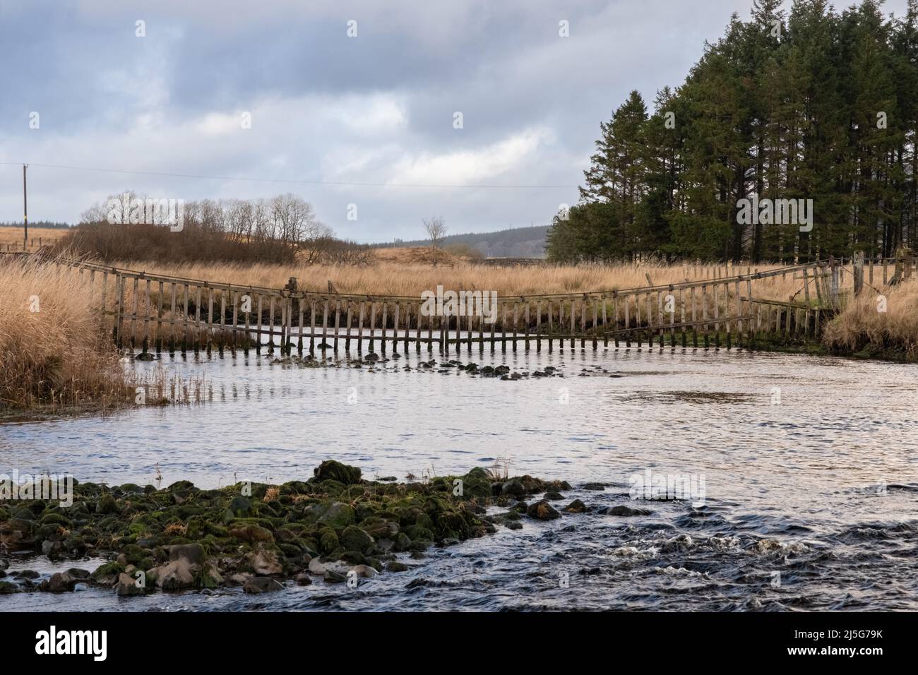A watergate hanging across the Carsphairn Lane River at the confluence with the Water of Deugh in winter, Dumfries and Galloway Scotland Stock Photo