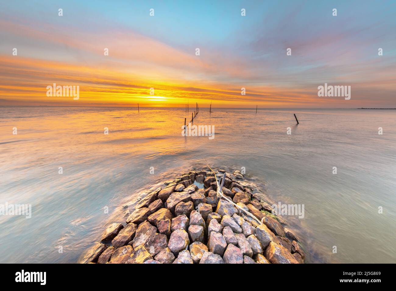 Typical basalt breakwater pier construction at  IJsselmeer near the town of Hindeloopen in the Friesland Province at sunset, Netherlands. Stock Photo