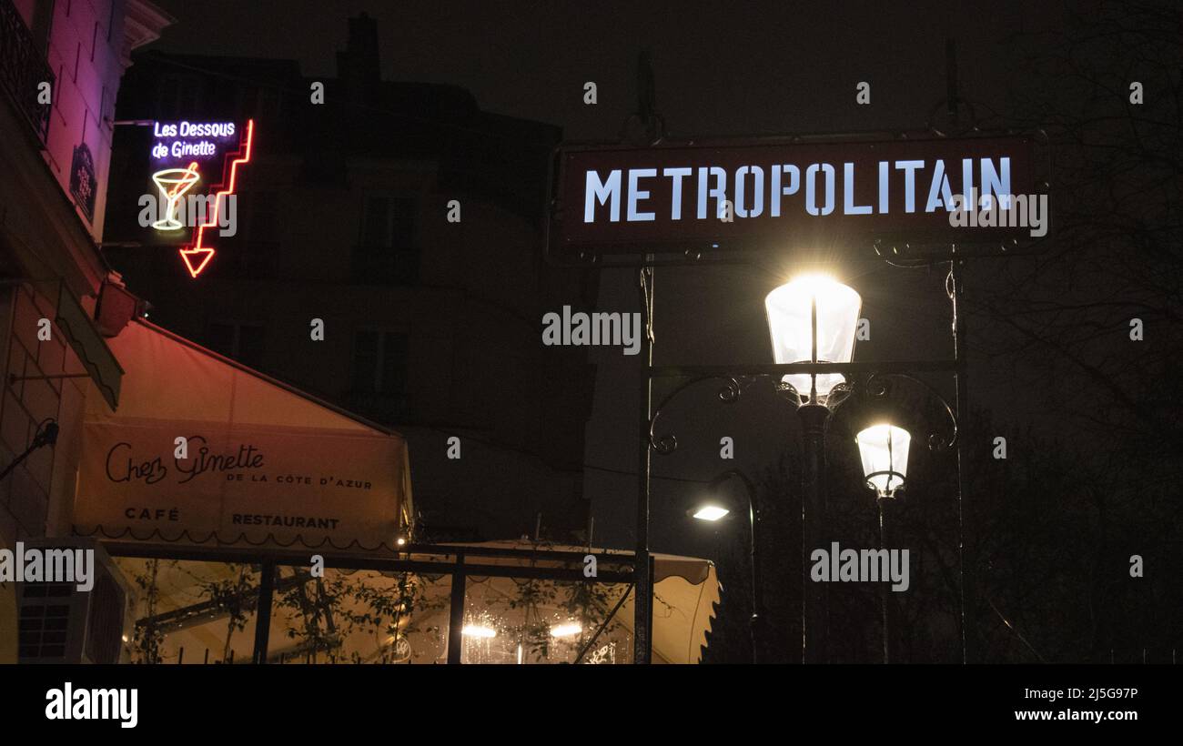 Paris, France: night view, street lamps and neon signs at the Montmartre metro station entrance, famous hill in the northern 18th arrondissement Stock Photo