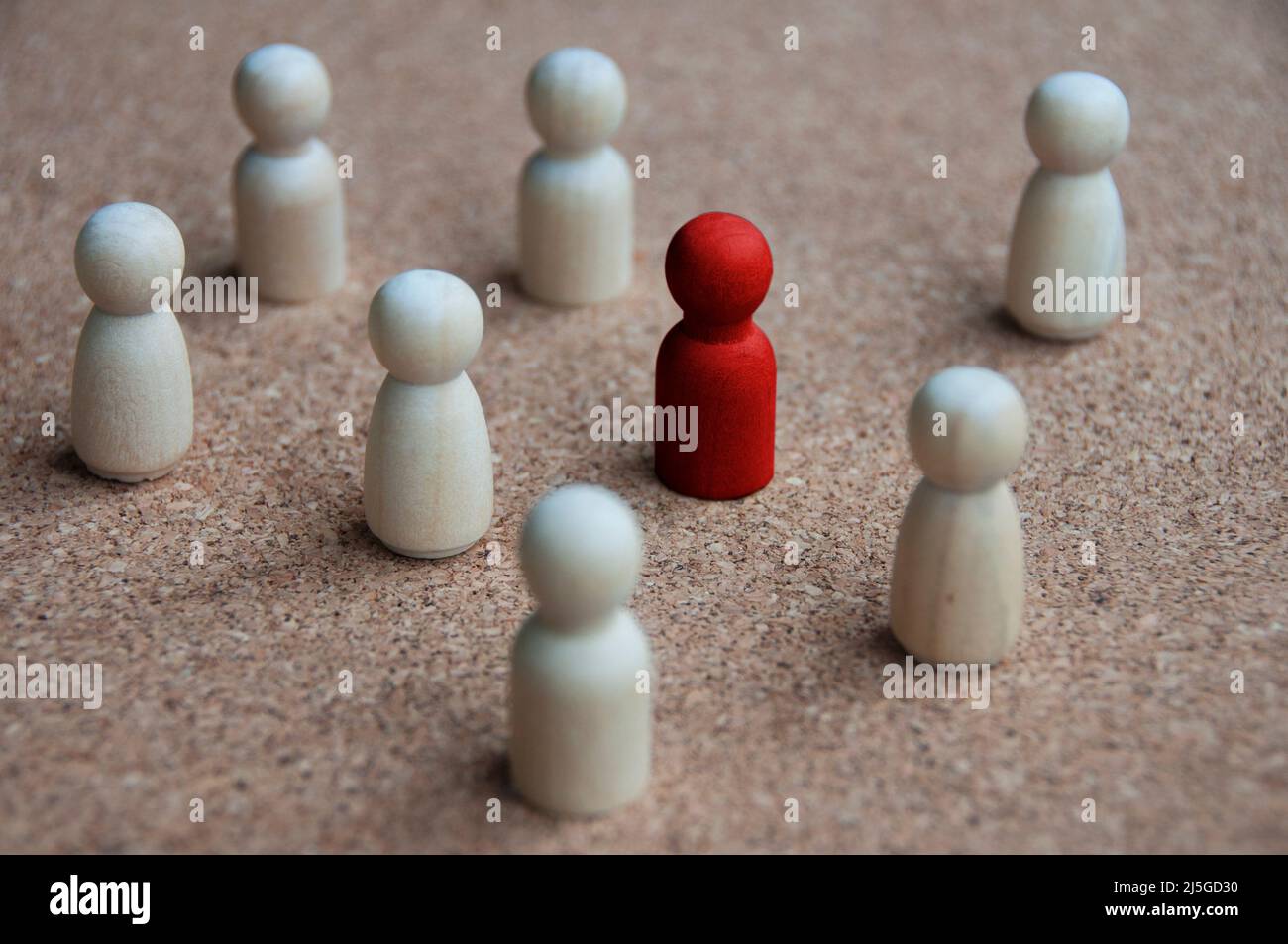 Red wooden doll figure surrounded by other doll figure. Harassment and bully concept. Stock Photo
