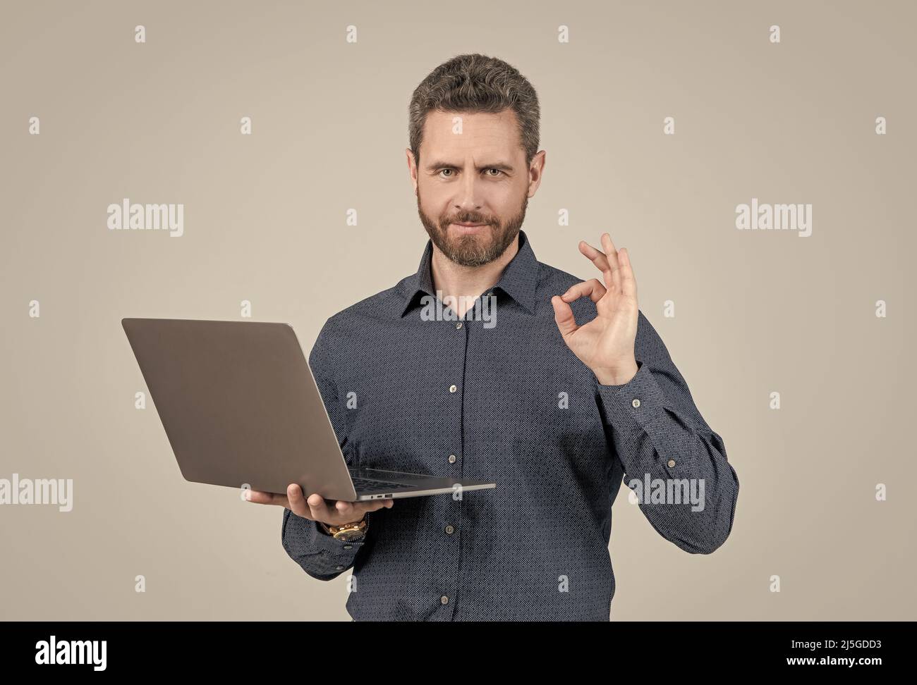 Computer programmer show ring gesture holding portable laptop grey background, OK Stock Photo