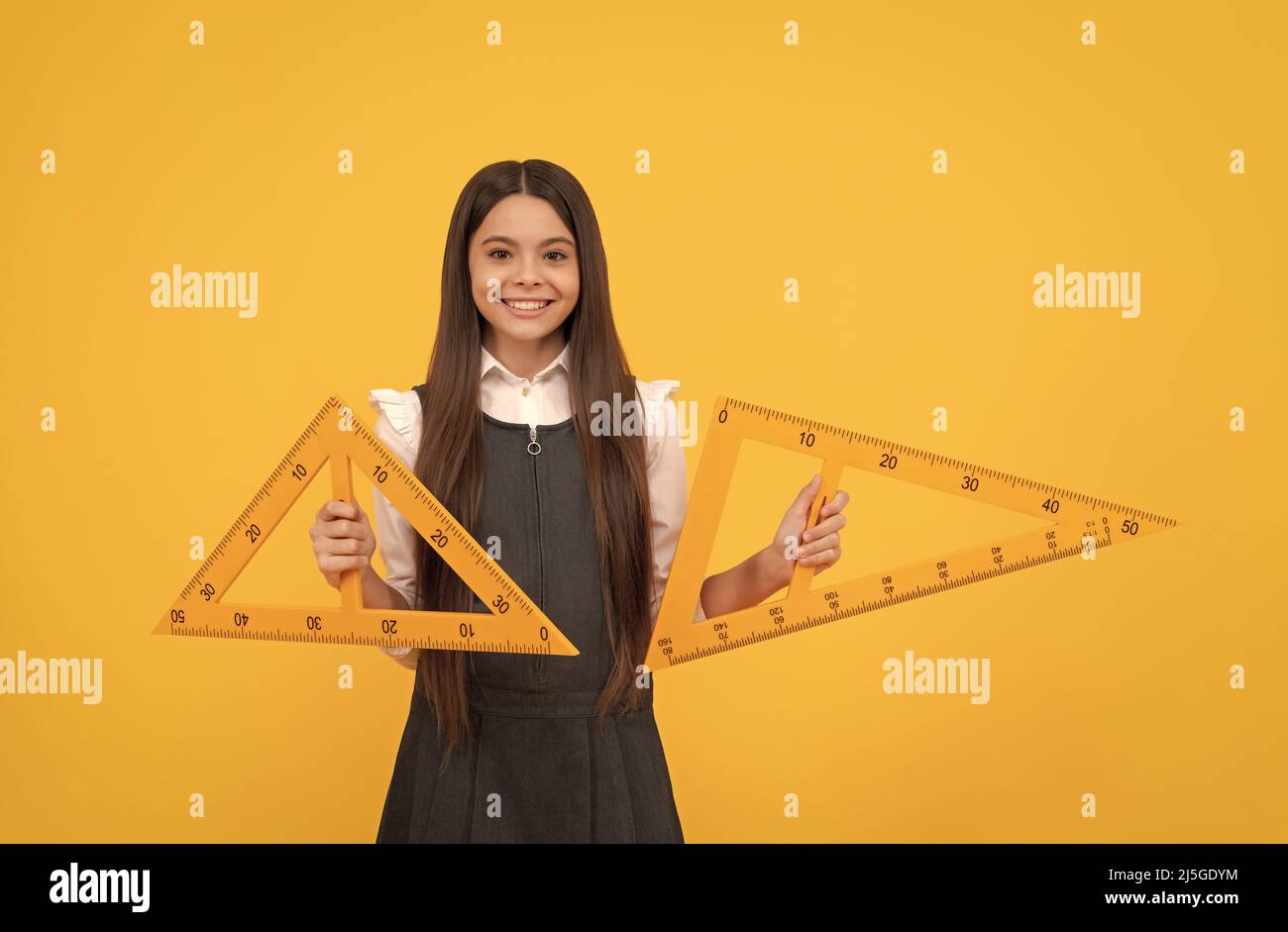 cheerful teen girl hold math triangle ruler in school on yellow ...